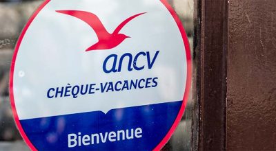 Sticker ANCV sur une vitrine indiquant l'acceptation des chèques-vacances.